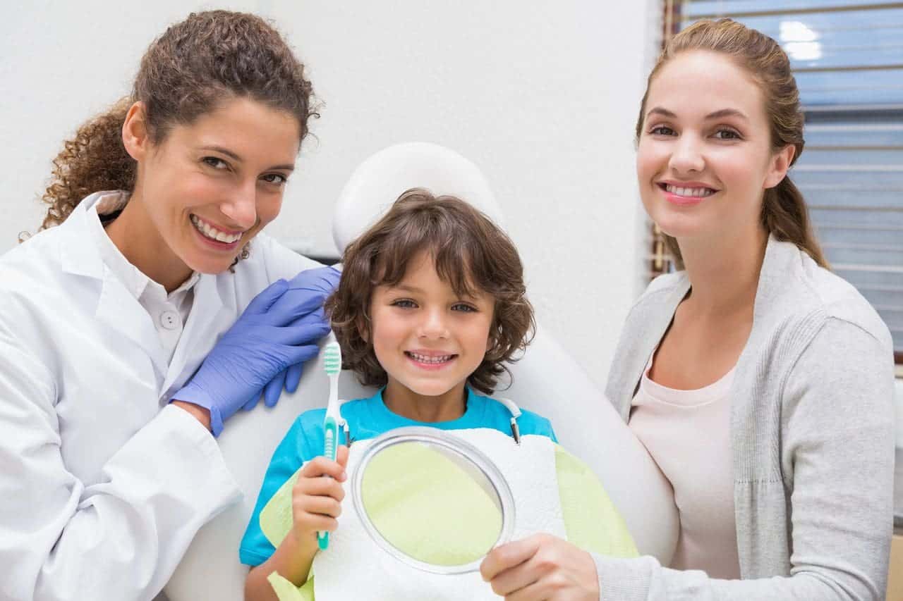 Odontologo pediatrico que muestra al nino como cepillar los dientes Odontologo pediatrico que muestra al nino como cepillar los dientes