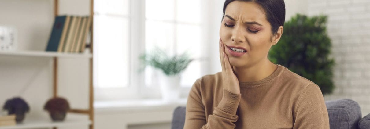 Mujer joven que sufre de dolor de muelas severo o sensibilidad de los dientes - problemas dentales mas comunes