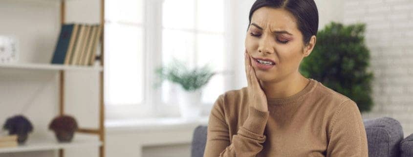 Mujer joven que sufre de dolor de muelas severo o sensibilidad de los dientes - problemas dentales mas comunes