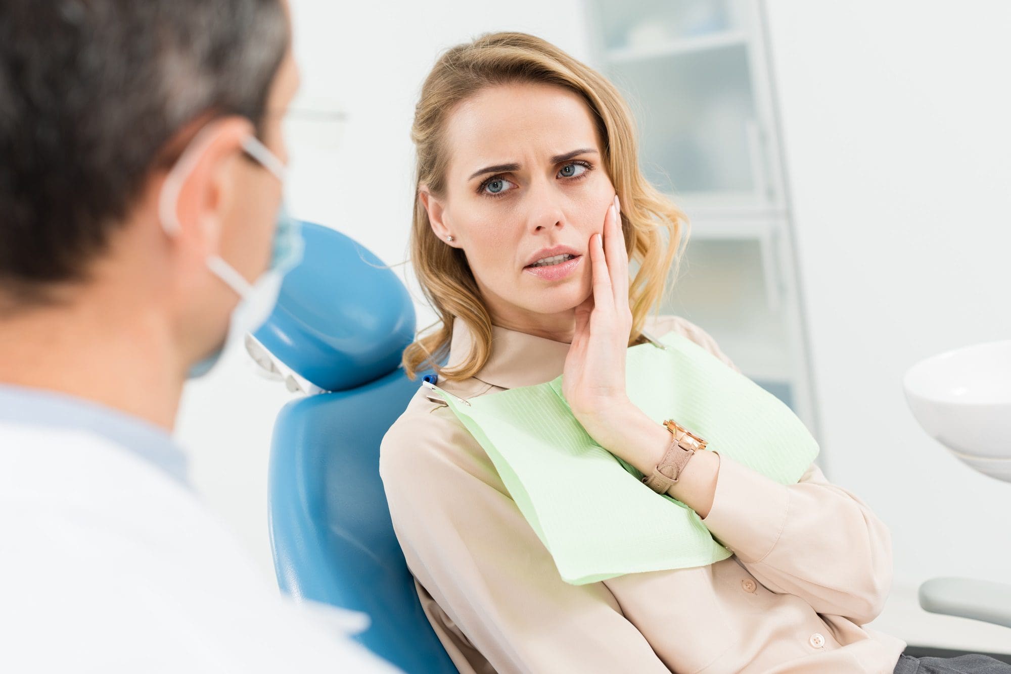 Paciente femenina preocupada por el dolor de muelas en la clínica dental - ir al dentista durante el confinamiento