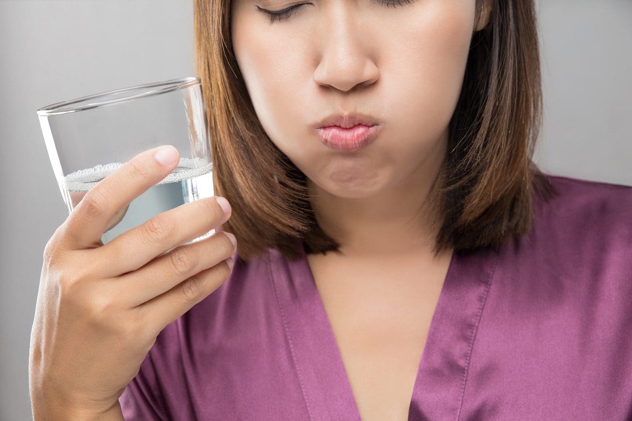 Mujer enjuague y hacer gárgaras mientras usa enjuague bucal - tratamiento halitosis