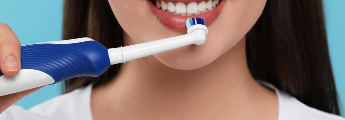 Tecnología y Cuidado Bucal en Casa: Complementando al Dentista 1 Mujer cepillándose los dientes con cepillo de dientes eléctrico - cuidado bucal en casa