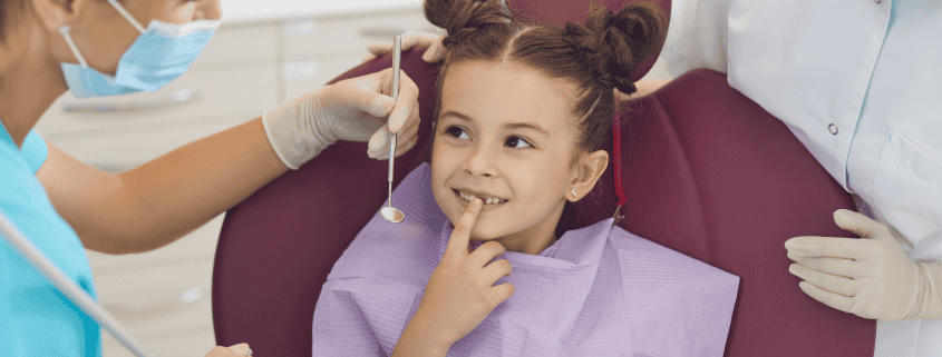 Salud bucal en niños: sellado dental y otros métodos de prevención 10 Odontopediatra enseñando un modelo dental a una niña pequeña durante su primera visita al dentista en Clínica Dental Benalúa Alicante