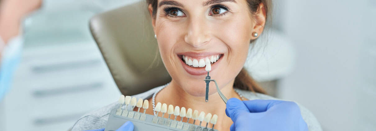 Carillas Dentales: Qué Son, Cuánto Duran y Cómo Saber Si Son Para Ti 1 Paciente sonriendo junto a una guía de color dental durante el diseño de carillas dentales en Clínica Dental Benalúa Alicante