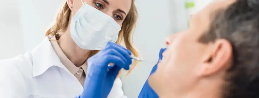 Causas y Tratamiento de los Dientes Negros 17 Dentista revisando los dientes de un paciente con espejo dental en la consulta