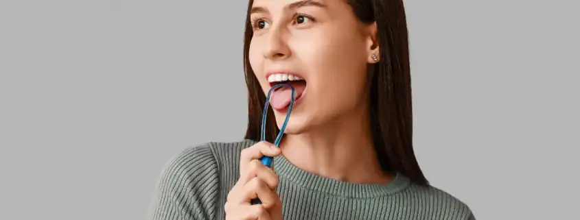 Mujer usando un limpiador lingual para limpiar la lengua